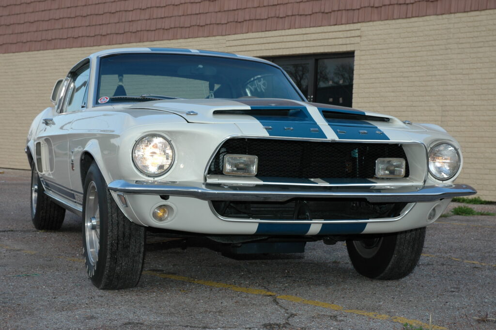 White Shelby Mustang with blue racing stripes, front three-quarter view